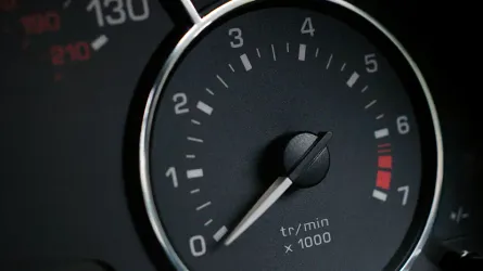 Close view of an illuminated tachometer needle and numbered engine-speed scale