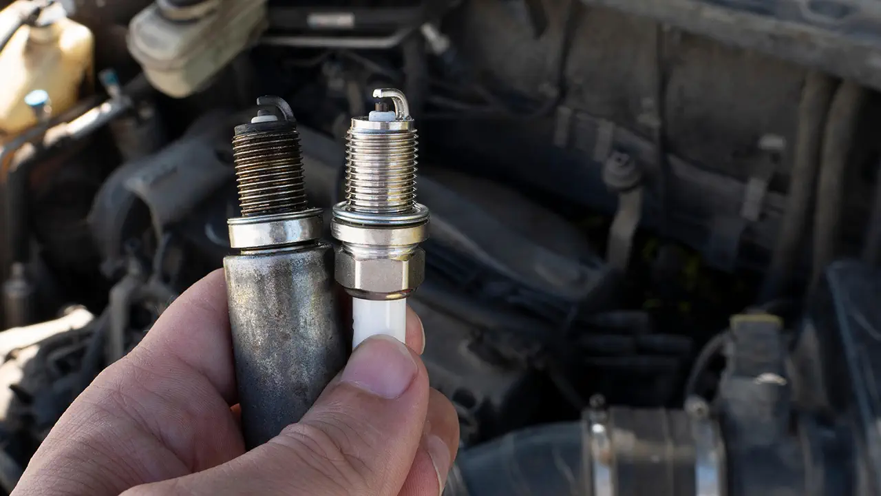 An old spark plug next to a worn one.